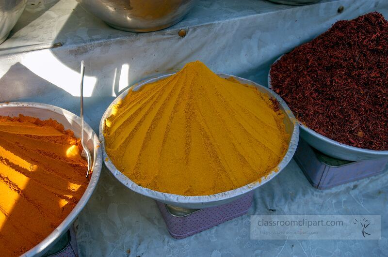 Vibrant piles of spices are artfully arranged in bowls at a bustling market in Aswan Egypt The bright yellow spice stands out under the sun showcasing local flavor