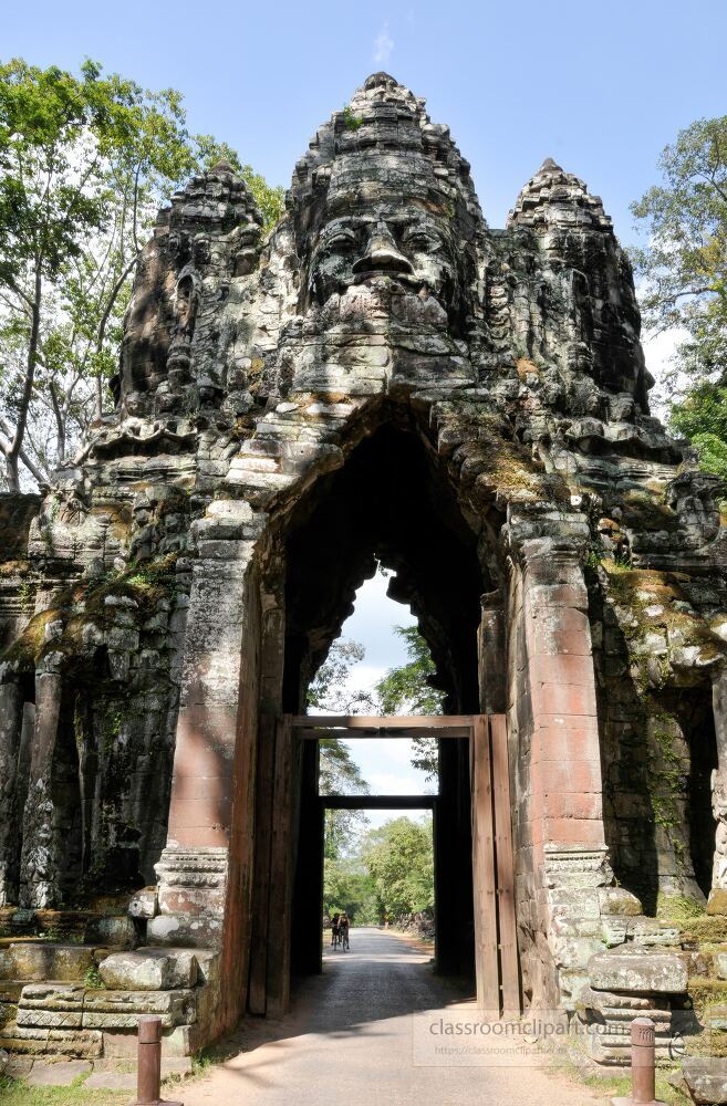 Majestic stone faces rise above the gates of Angkor Wat in Siem Reap Cambodia where ancient architecture meets lush greenery under a bright blue sky inviting exploration of cultural treasures.