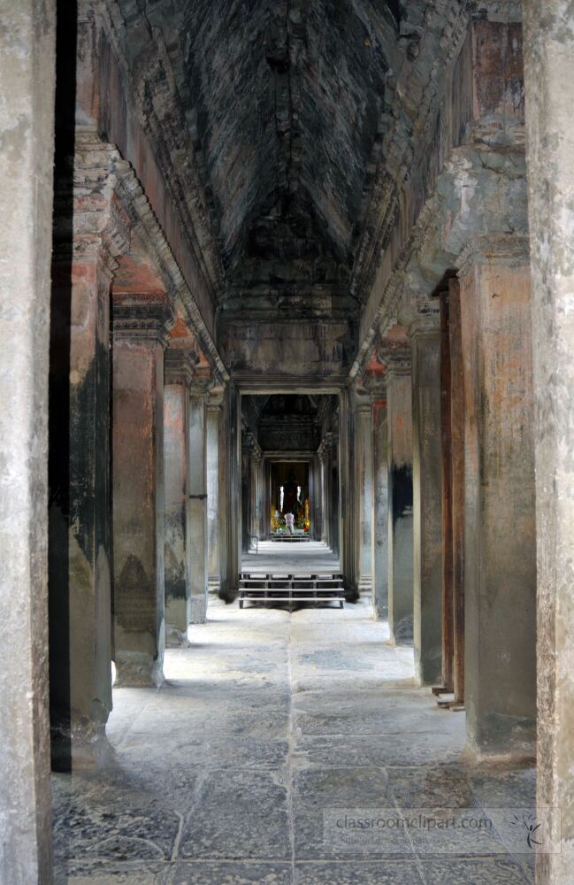 Ancient stone passageways beckon with history in Angkor Wat. Visitors wander through sacred corridors marveling at intricate carvings and the serene atmosphere of this UNESCO World Heritage site at twilight.