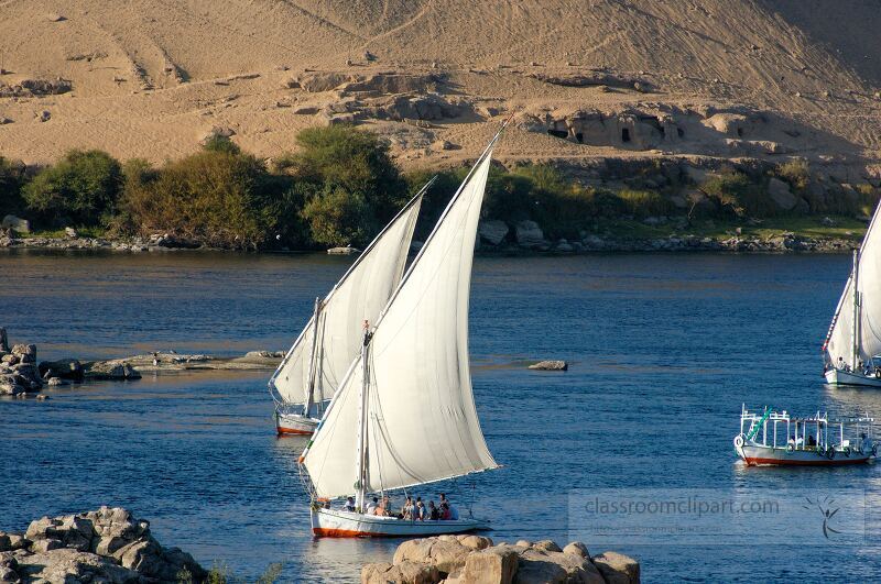 Traditional sailing boats navigate the calm waters of the Nile River near Aswan showcasing the beauty of Egypts landscape and connecting with local culture during daylight